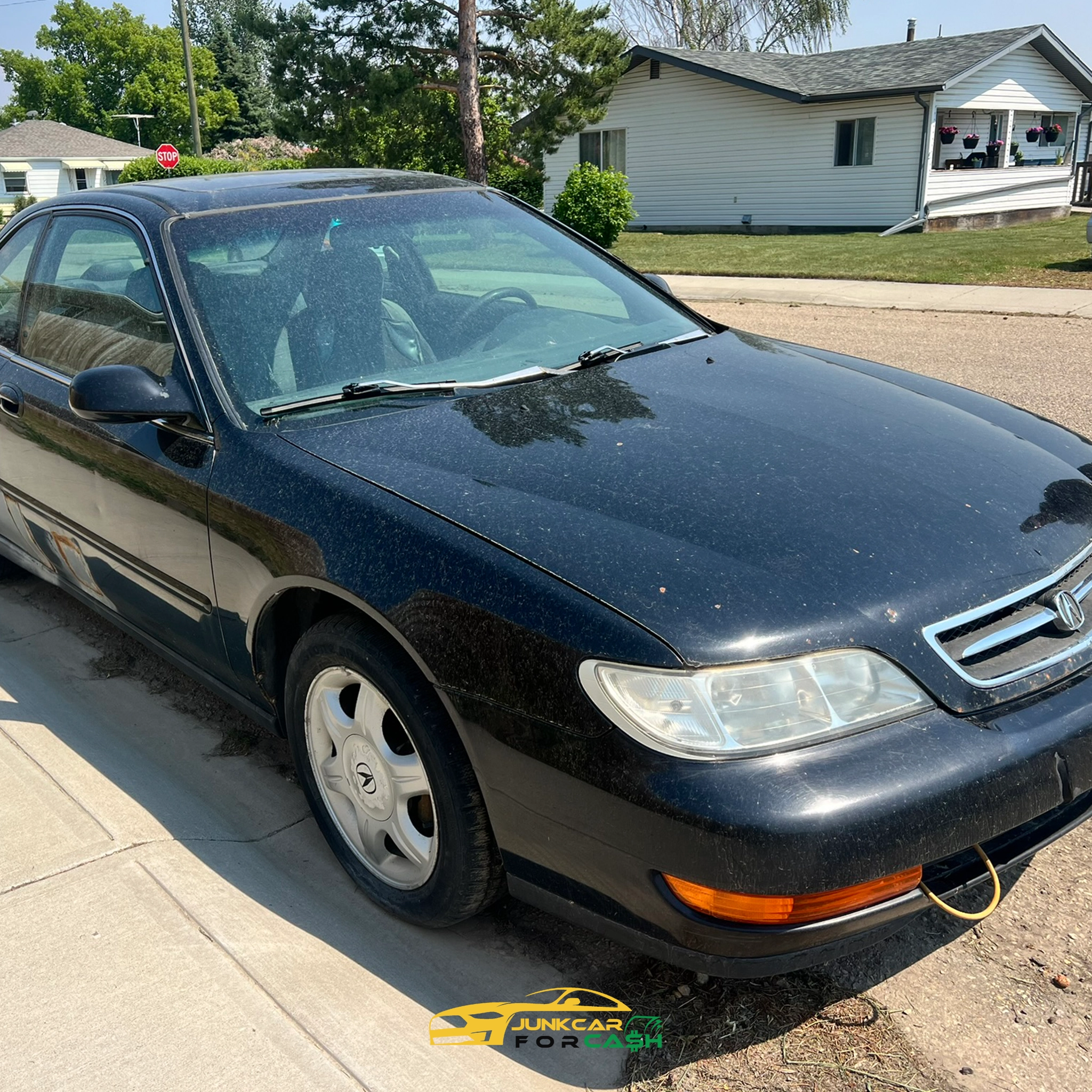 "Black Acura CL coupe with yellow tow strap on front bumper parked on suburban street beside sidewalk and trees."