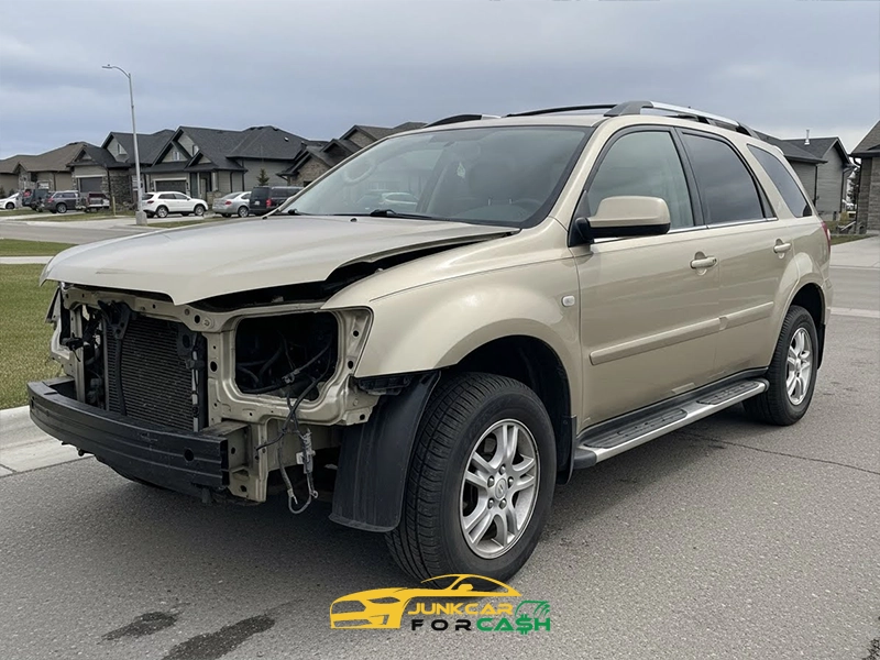 Beige SUV parked on a residential street with the front bumper and headlights removed, exposing internal components and visible body damage.